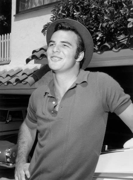 American actor Burt Reynolds smiles leans an automobile wearing a - Old Photo
