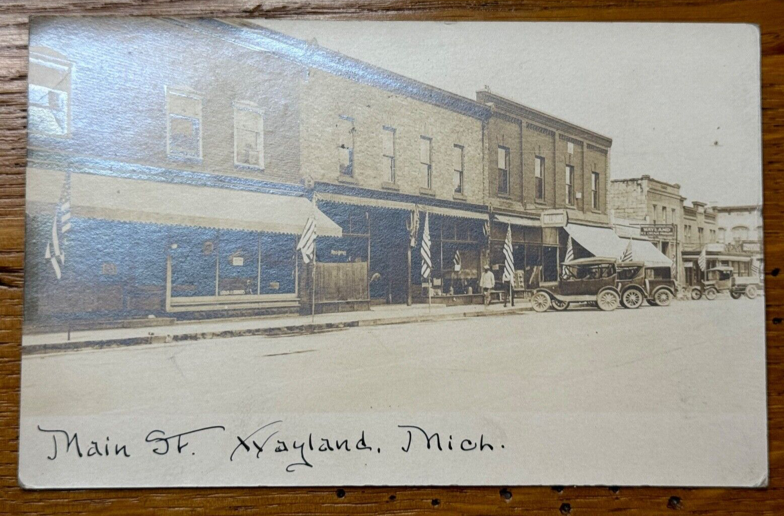Vintage Main St Street Wayland Michigan MI Cars Flag RPPC Real Photo Postcard