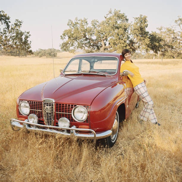 Young woman leaning against vintage car Historic 1960s Old Photo