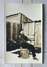 Antique RPPC Man Sitting On Crate Outside In Snow picture
